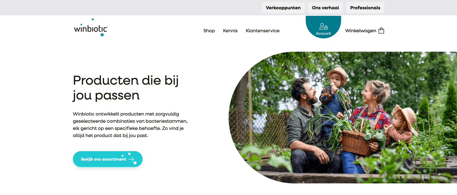Winbiotic is presented with a clean landing page featuring a Dutch headline “Producten die bij jou passen” and a teal call-to-action button “Bekijk ons assortiment,” alongside a rounded photograph of a cheerful family outdoors in a garden, illustrating the brand’s focus on personalised bacterial strain combinations.